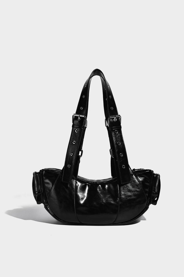 Glossy black crescent shoulder bag with silver-tone rivets, multiple zip pockets, and long adjustable studded straps, detail