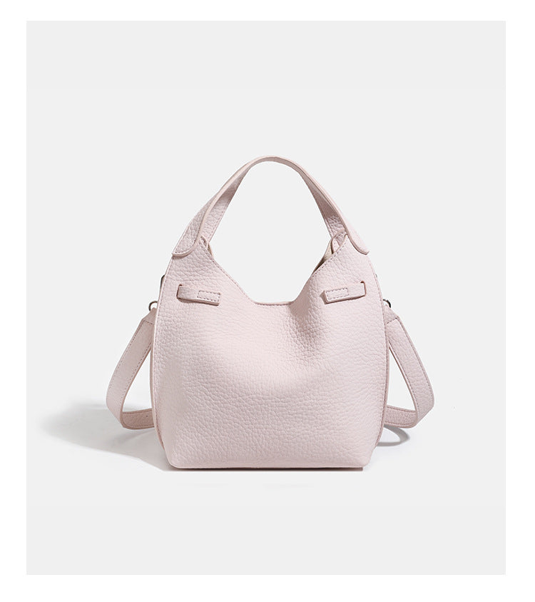 Compact pebbled leather-look shoulder bag with crossed silver-toned metal front closure, short top handle, and long, detail