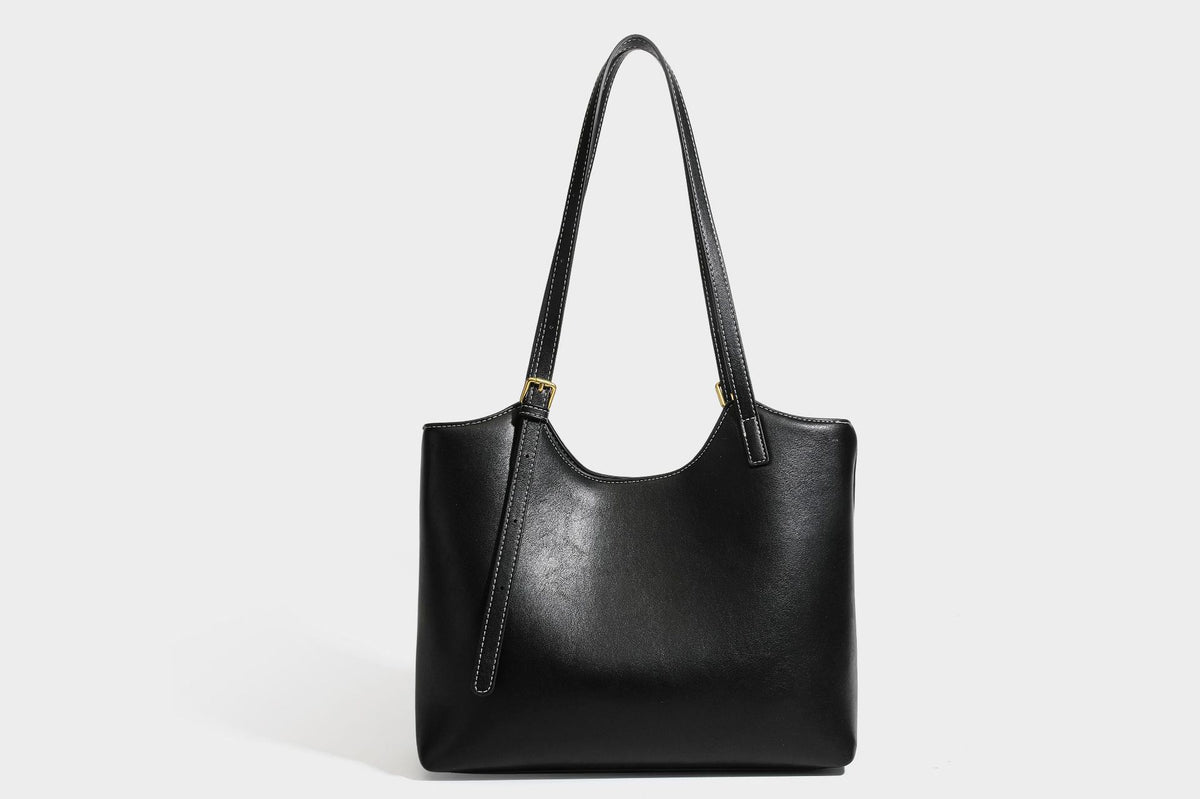 Structured smooth leather-look tote bag with long shoulder strap, gold-tone hardware, and hanging tassel-coin charm, detail