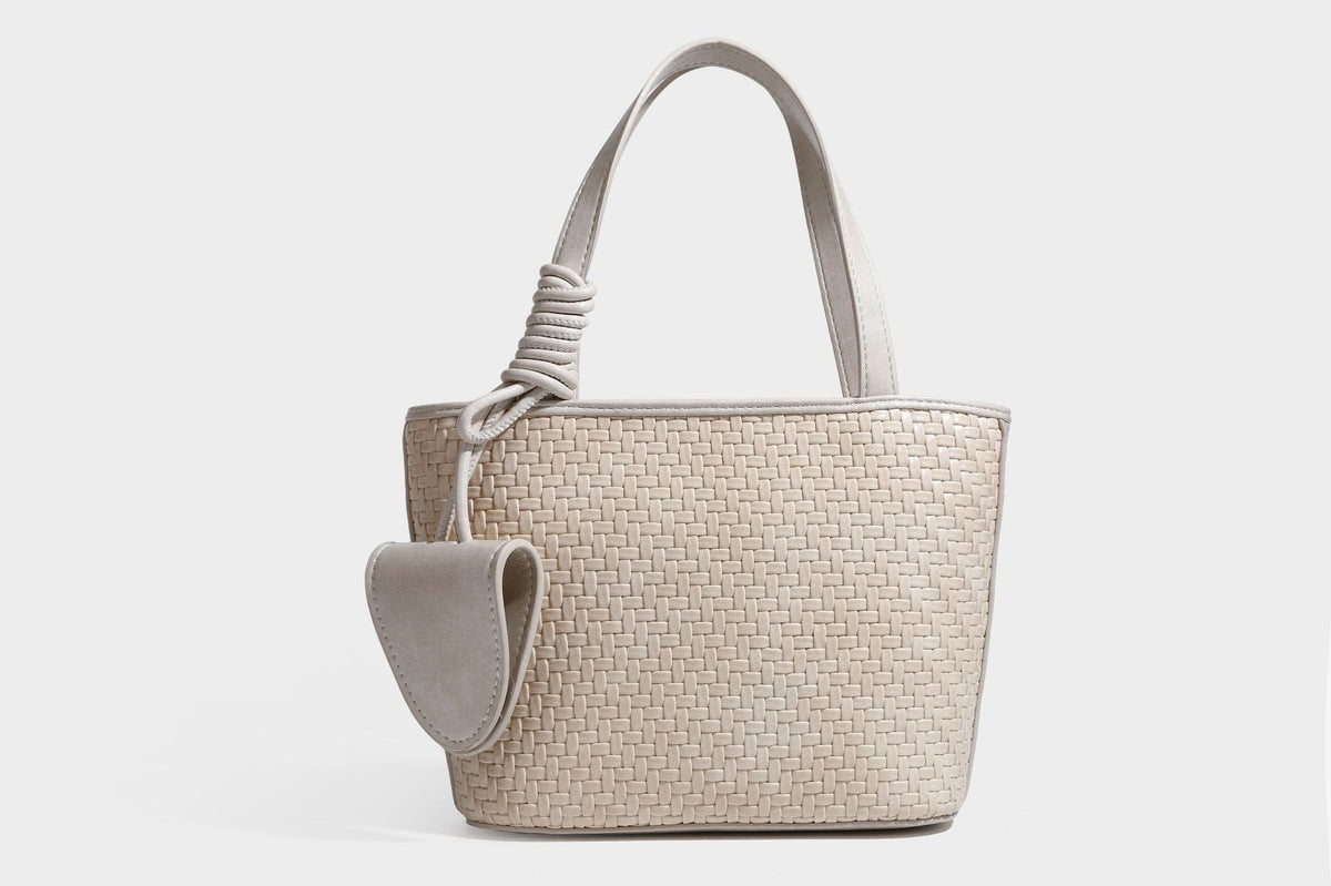 Strukturierte Tote Bag mit gewebter Oberfläche in Braun, goldfarbenen Metalldetails, seilumwickelten Tragegriffen, einer kleinen Fronttasche und weiteren Details