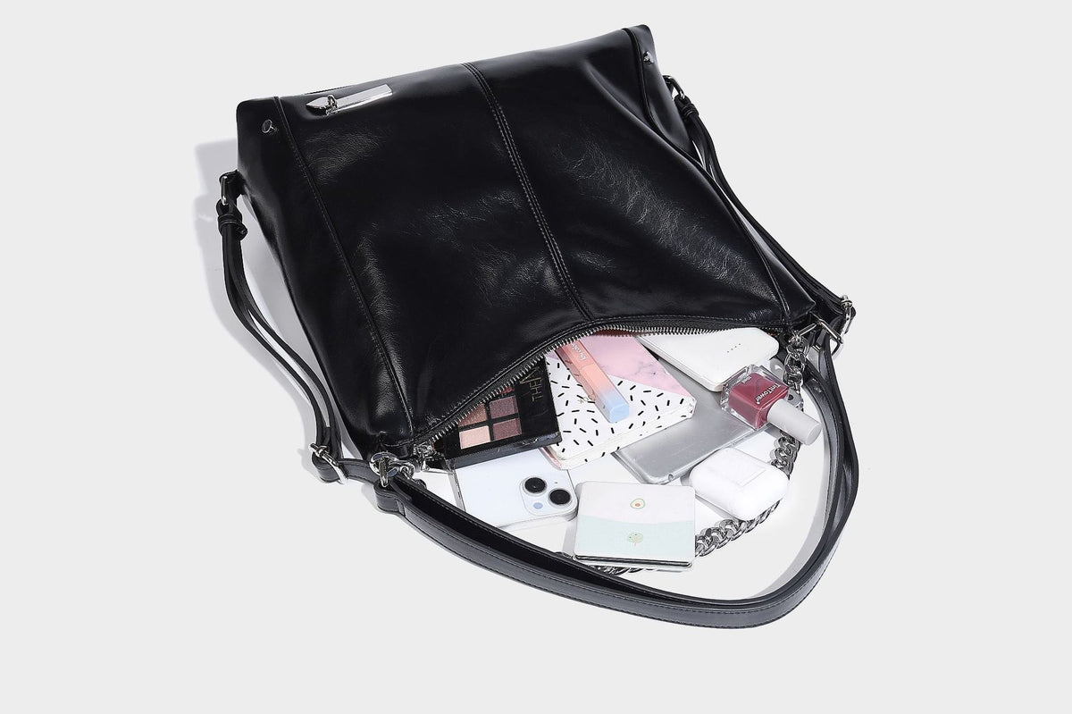 Glänzend schwarze Hobo-Shopper-Tasche mit silberfarbenem Kettenakzent, Reißverschluss oben und langen Schulterriemen, Detailansicht 25