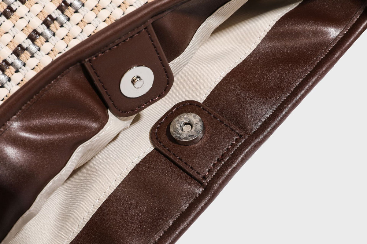 Woven stripe bucket shoulder bag in cream and dark brown with leather-look trim, knotted adjustable strap, and small shield