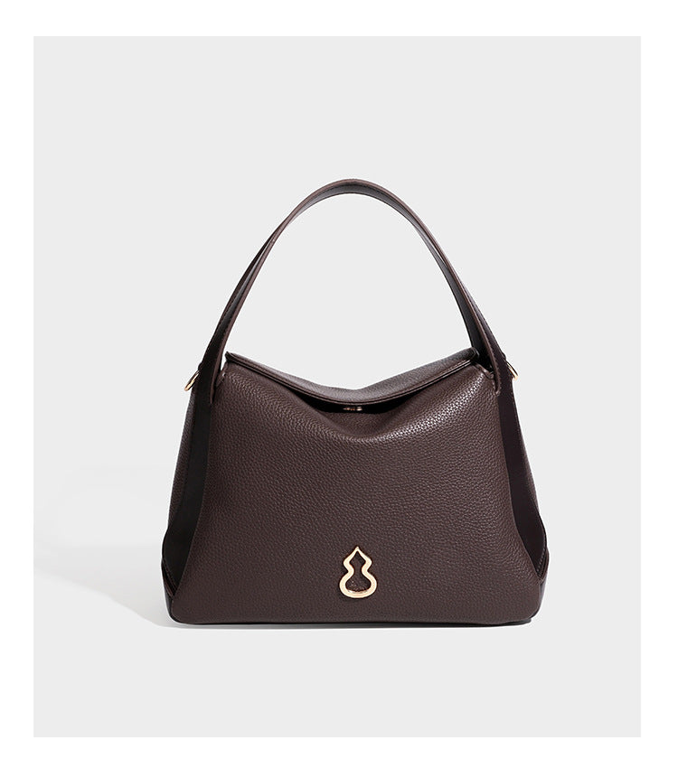 Structured pebbled leather-look shoulder bag with flap top, gold-tone emblem hardware, dual top handles, and detachable