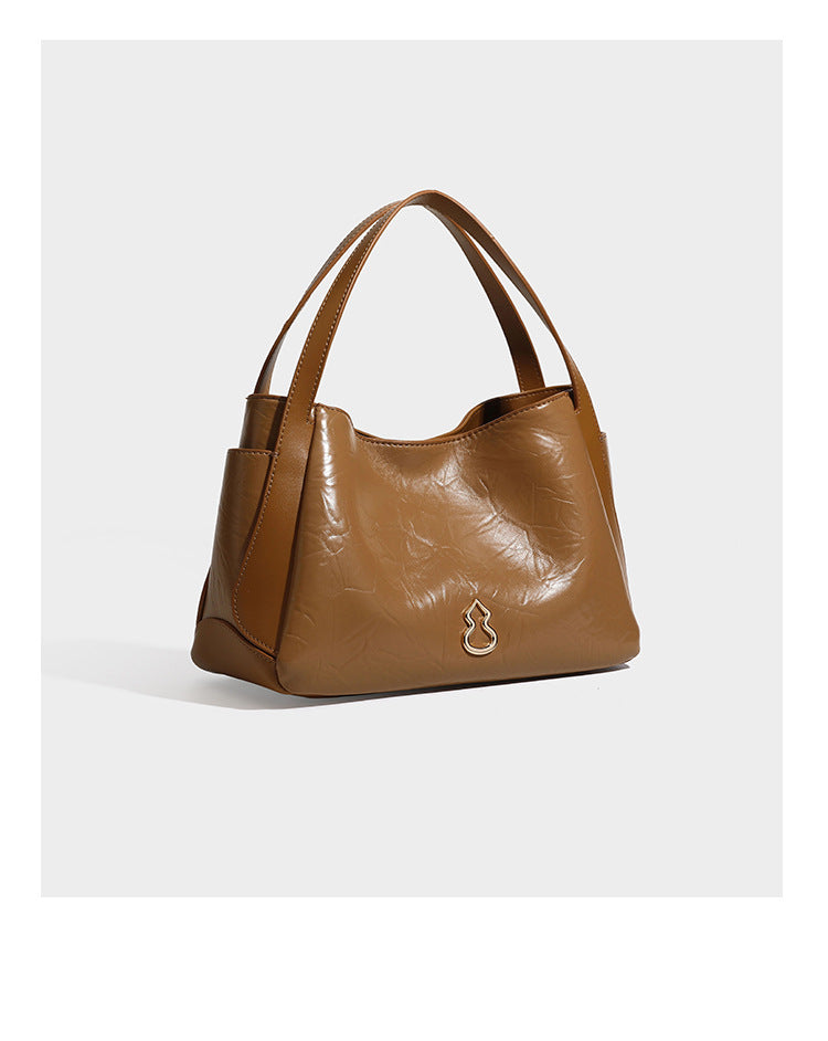 Black glossy crinkled leather-look convertible shoulder tote bag with gold gourd-shaped emblem hardware and detachable