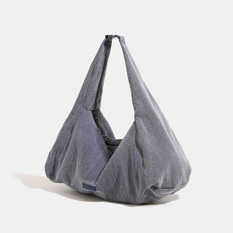 Oversized slouchy black textured canvas hobo shoulder bag with zip-top closure and adjustable dark-hardware strap, detail