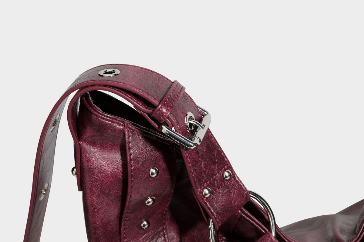Lässige Hobo-Schultertasche in glänzender Lederoptik mit silberfarbenen Nieten, Riemendetail mit Schnalle und Reißverschluss oben