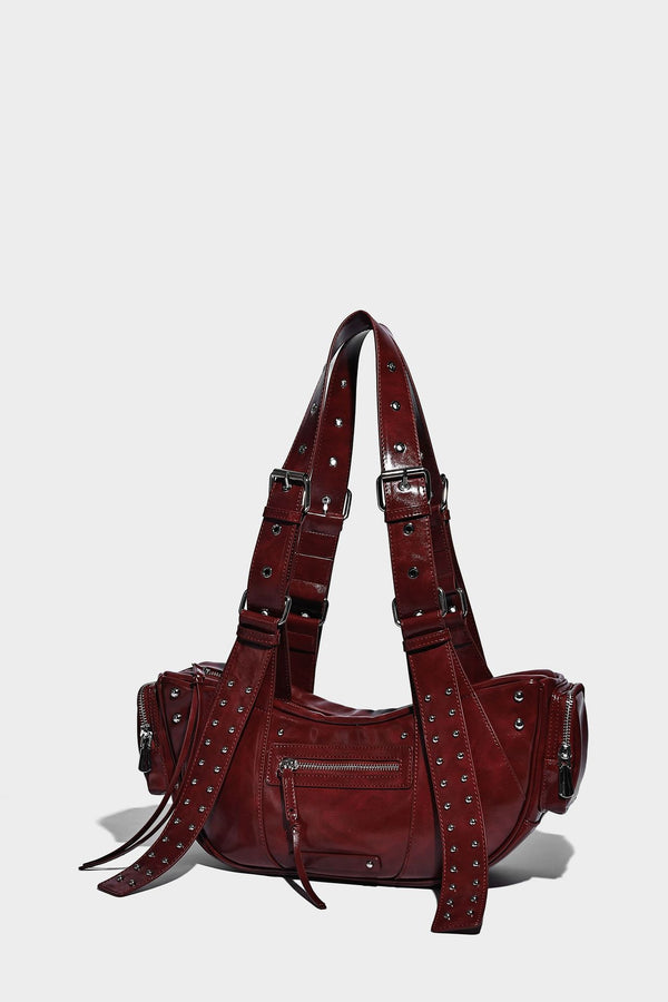 Glossy black crescent shoulder bag with silver-tone rivets, multiple zip pockets, and long adjustable studded straps, detail