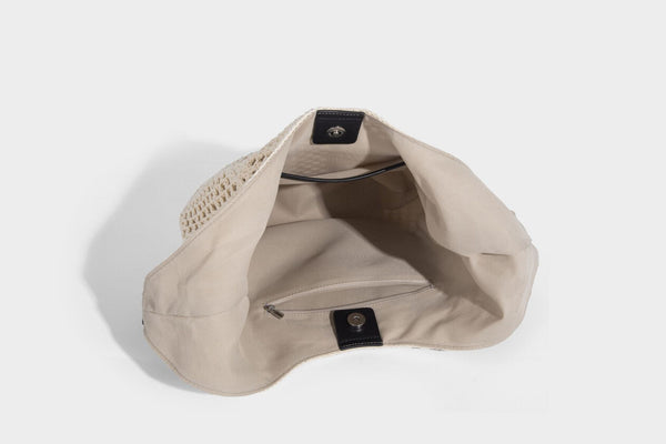 Cream openwork crochet hobo bag with black leather-look strap and trim patch accent, slouchy teardrop silhouette, detail view