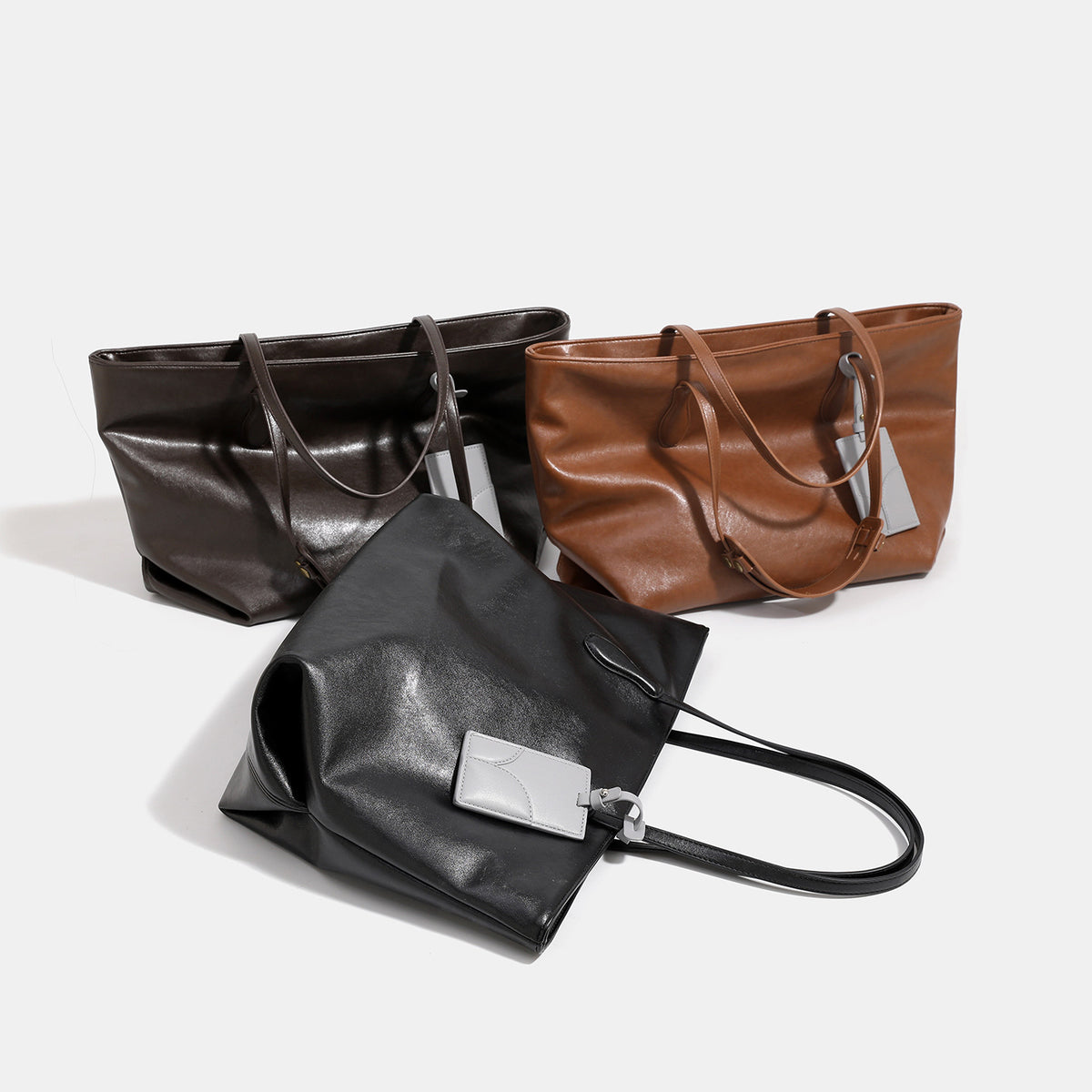 Large soft trapezoid tote bag with leather-look finish, dual shoulder straps, and gray hanging card tag, detail view 2