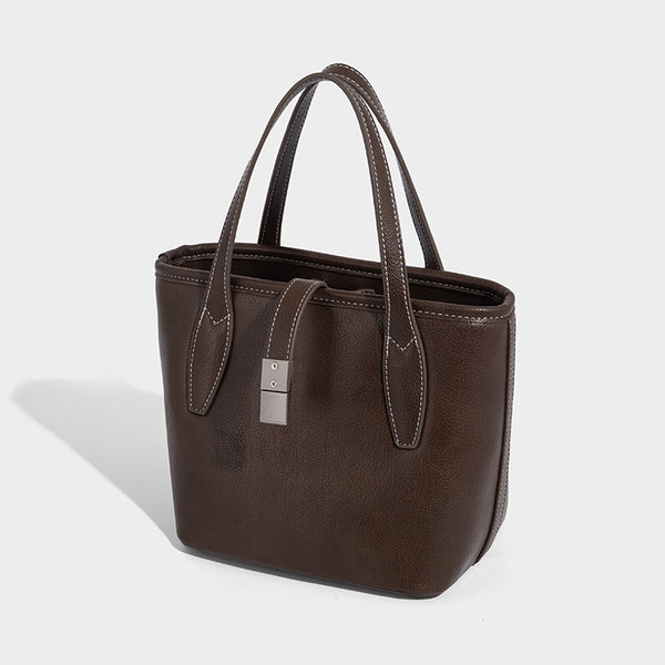 Compact structured bucket tote bag with pebbled textured finish, dual top handles, silver-tone lock hardware, and detachable