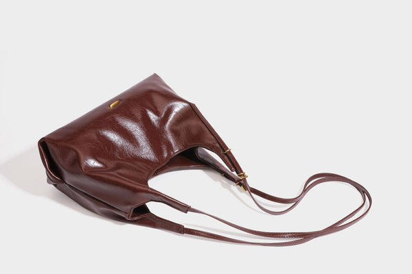 Locker fallende Hobo-Schultertasche mit offenem Oberteil aus glänzendem, geknautschtem Lederimitat in Dunkelbraun, mit schmalem verstellbarem Riemen und goldfarbenem