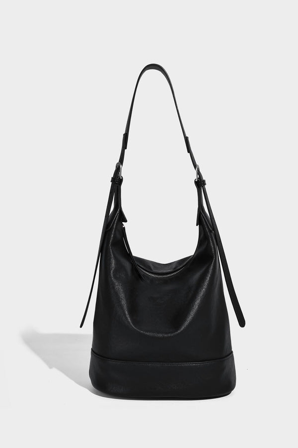 Slouchy bucket hobo shoulder bag in dark brown with glossy leather-look finish, top zip closure, and long adjustable, detail