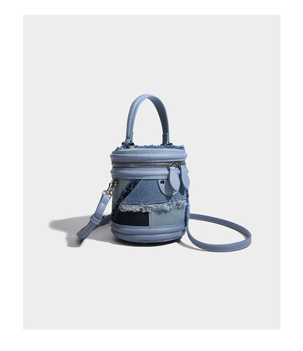 Mini cylindrical barrel bucket bag in denim patchwork with frayed edges, smooth leather-look trim, zip-around top closure