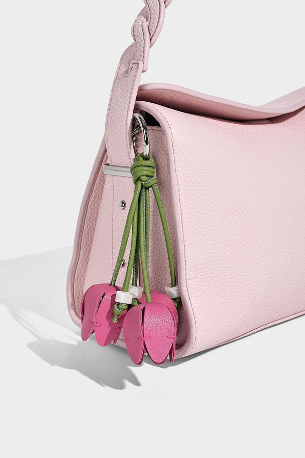 Small structured pebbled-finish shoulder bag with braided top handle, detachable crossbody strap, floral tassel charm, and