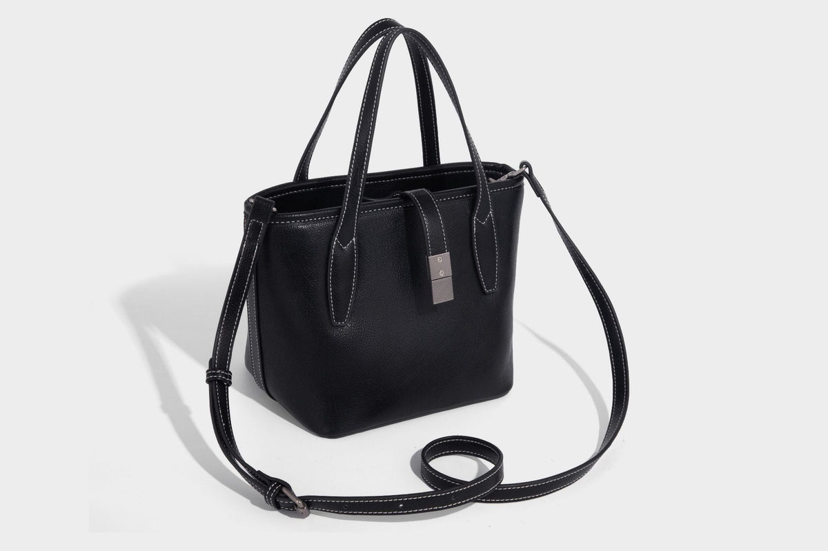 Compact structured bucket tote bag with pebbled textured finish, dual top handles, silver-tone lock hardware, and detachable