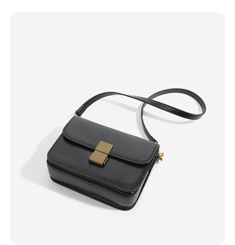 Mini structured black flap crossbody bag with gold-tone ribbed rectangular clasp and adjustable shoulder strap, detail view 9