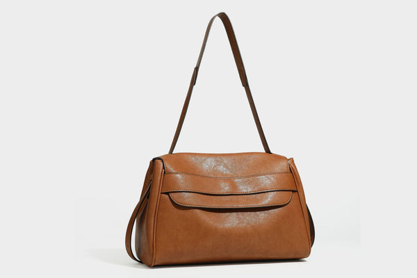 Strukturierte rechteckige dunkelbraune Schultertasche in Lederoptik mit Klappe, mehrlagigem Detail auf der Vorderseite und langem verstellbarem Riemen, Detailansicht