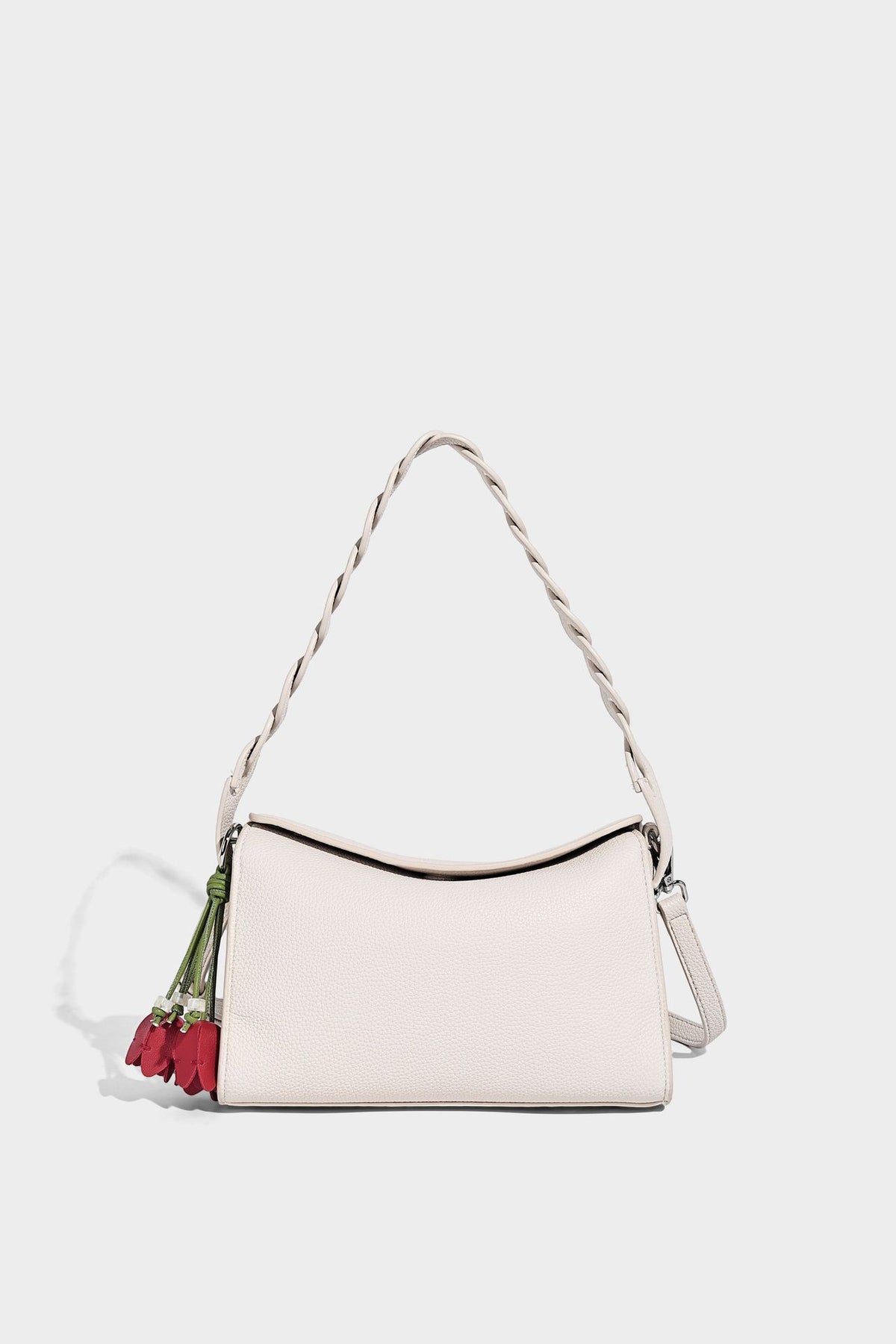 Small structured pebbled-finish shoulder bag with braided top handle, detachable crossbody strap, floral tassel charm, and
