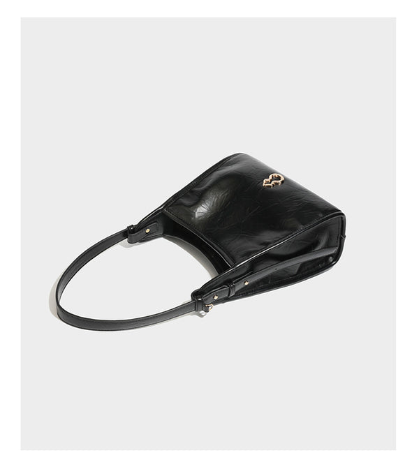 Strukturierte, trapezförmige Schultertasche aus glänzender, geknautscht wirkender Lederoptik mit goldfarbenen Beschlägen auf der Vorderseite und langem, verstellbarem