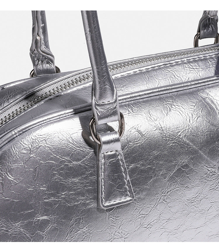 Rounded rectangular shoulder bag with glossy crinkled finish, dual long handles, top zip closure, and gingham ribbon bow