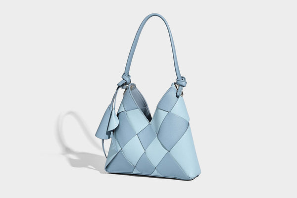 Compact bucket shoulder bag with black-and-white diamond patchwork panels, knotted top handle, gold-tone hardware, and