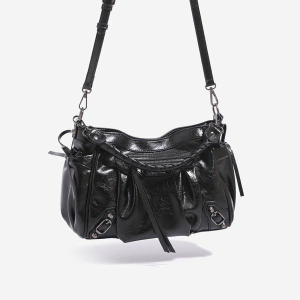 Slouchy glossy crinkle leather-look shoulder bag with silver stud accents, tassel ties, front zip pocket, and top handle