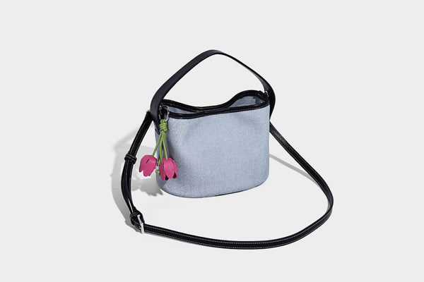 Hellblaue Bucket-Bag aus Denim mit schwarzem Besatz in Lederoptik, silberfarbenen Beschlägen, kurzem Tragegriff und langem verstellbarem Crossbody-Riemen
