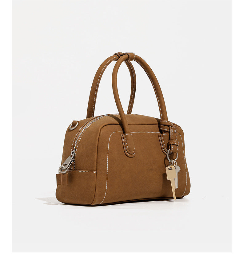 Kompakte, strukturierte Henkeltasche mit matter genarbter Oberfläche, geknoteten Doppelhenkeln, goldenem Schlüsselanhänger und abnehmbarem, Detail