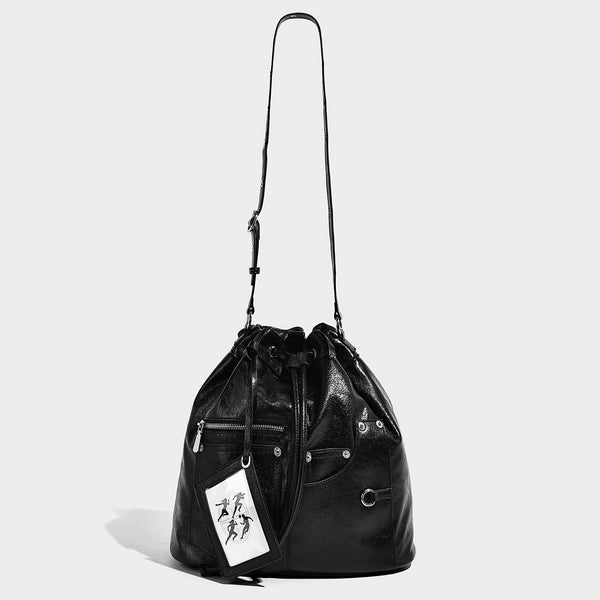 Glossy black convertible bucket backpack with silver grommet-studded straps, drawstring cinch closure, and front zip pocket