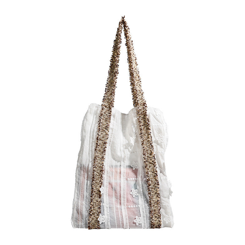 Offwhitefarbener weicher Canvas-Schultershopper mit offenen Seiten und braun-goldfarbenen Jacquard-Gurtbändern mit Blumenmuster, lässig rechteckige Form, Detailansicht