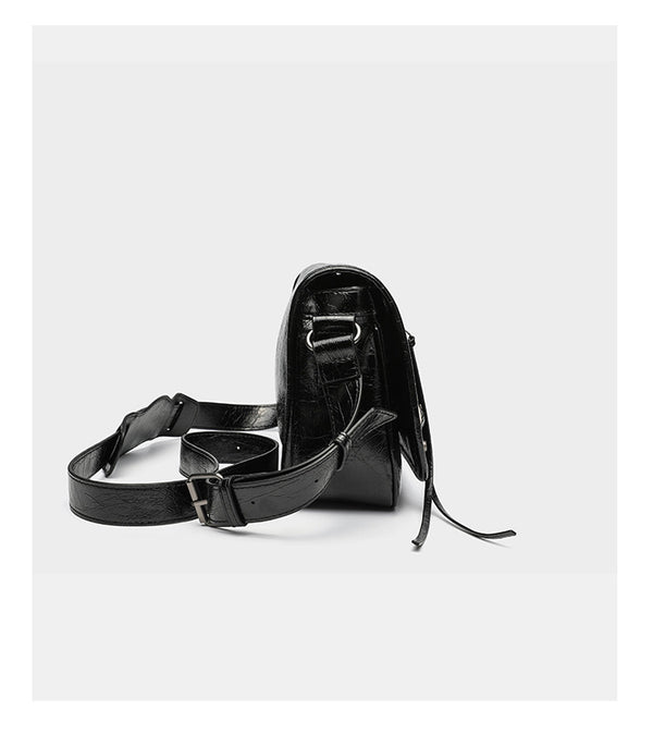 Small structured rectangular crossbody bag with crinkle leather-look finish, front zip pocket, gunmetal stud hardware, and