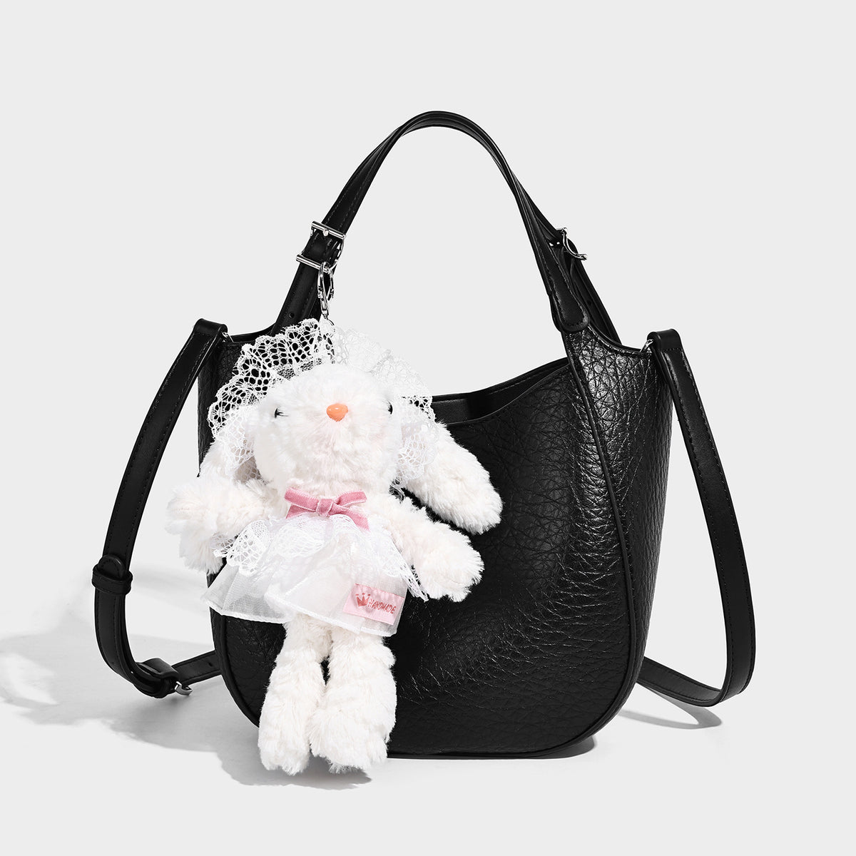 Small pebbled half-moon shoulder bag with dual top handles, detachable crossbody strap, and silver-tone hardware, detail view