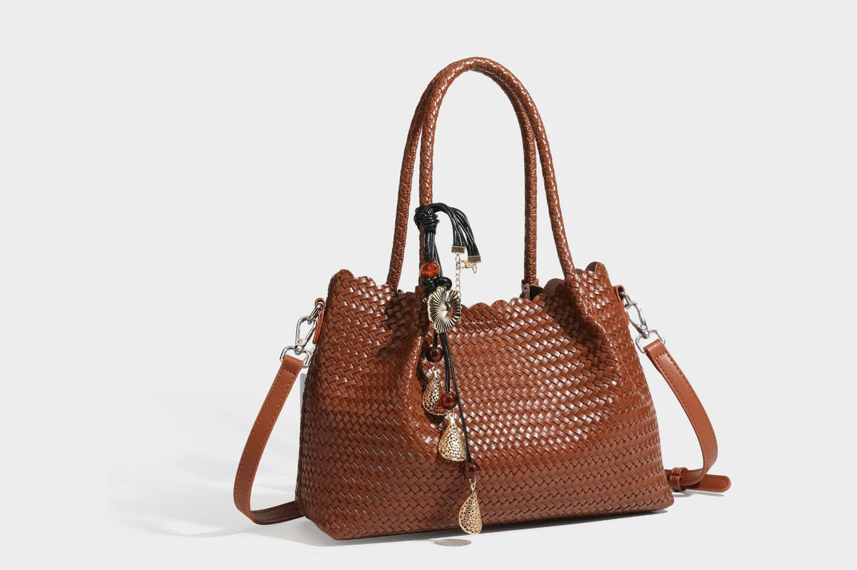 Strukturierter, glänzend geflochtener Shopper mit Muschelkantenabschluss am oberen Rand, geflochtenen Tragegriffen, abnehmbarem Crossbody-Riemen und Perlenquaste