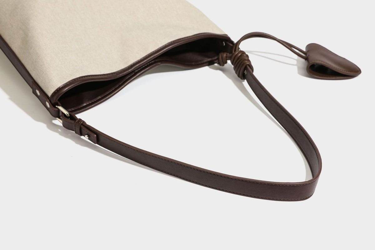 Oatfarbene Canvas-Schultertasche mit dunkelbraunem Besatz in Lederoptik, langem verstellbarem Riemen und angebrachter Mini-Tasche mit Überschlag, Detailansicht