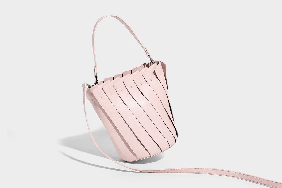 Structured pleated-panel bucket bag with curved top handle and detachable adjustable shoulder strap in smooth matte, detail