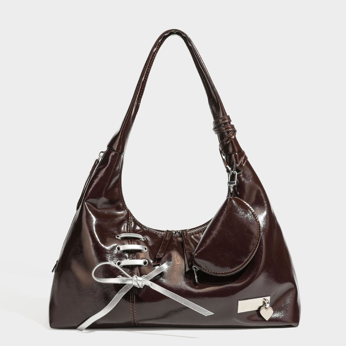 Weich fallende Hobo-Schultertasche in glänzender Lederoptik mit silberfarbenen Ösen zum Schnüren und Schleifenband auf der Vorderseite, Detailansicht