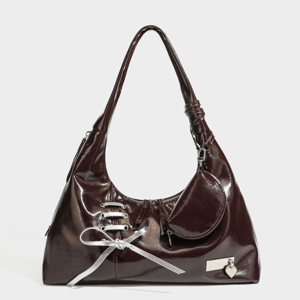 Weich fallende Hobo-Schultertasche in glänzender Lederoptik mit silberfarbenen Ösen zum Schnüren und Schleifenband auf der Vorderseite, Detailansicht
