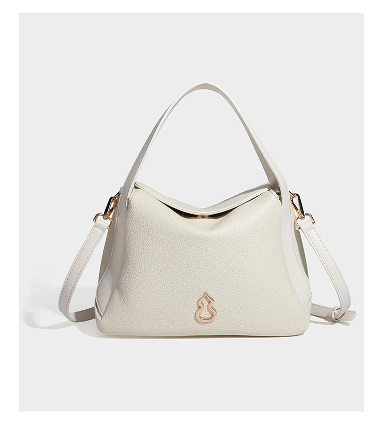 Structured pebbled leather-look shoulder bag with flap top, gold-tone emblem hardware, dual top handles, and detachable