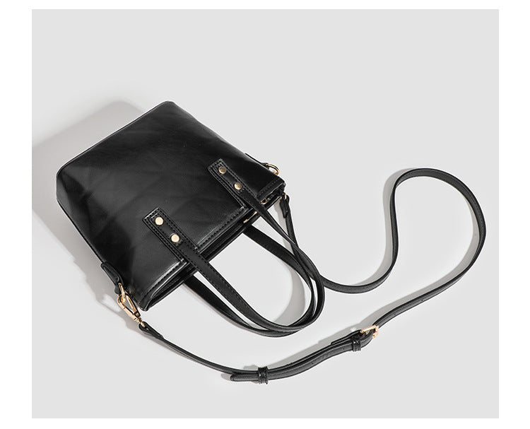 Kleine, formstabile Tote-Tasche mit Henkeln und Besatz in brauner Lederoptik auf einem cremefarbenen Korpus, Reißverschluss oben, goldfarbenen Nieten und
