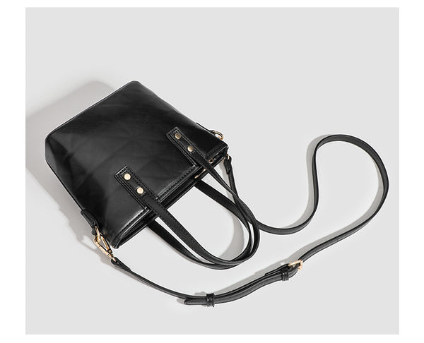 Kleine, formstabile Tote-Tasche mit Henkeln und Besatz in brauner Lederoptik auf einem cremefarbenen Korpus, Reißverschluss oben, goldfarbenen Nieten und