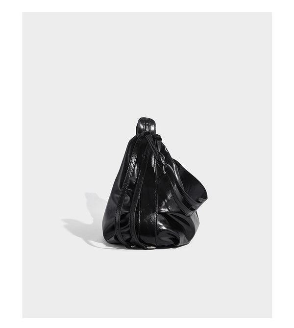 Glossy black slouchy hobo shoulder bag with zip closure, silver-tone ring hardware, and adjustable crossbody strap, detail