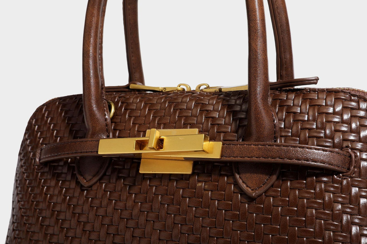 Structured woven-embossed leather-look satchel with dual rolled top handles, gold-tone turn-lock closure, and detachable
