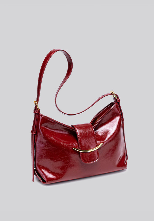 Glossy burgundy leather-look shoulder bag with curved gold-tone bar front closure, crinkled oil-wax texture, and adjustable