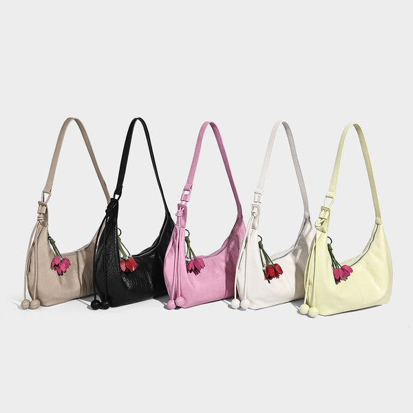 Slouchy crescent half-moon shoulder bag in pink pebbled textured finish with floral charm and knotted side detail, detail
