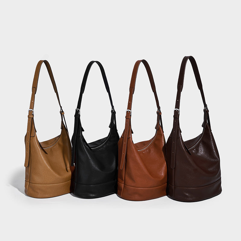 Slouchy bucket hobo shoulder bag in dark brown with glossy leather-look finish, top zip closure, and long adjustable, detail