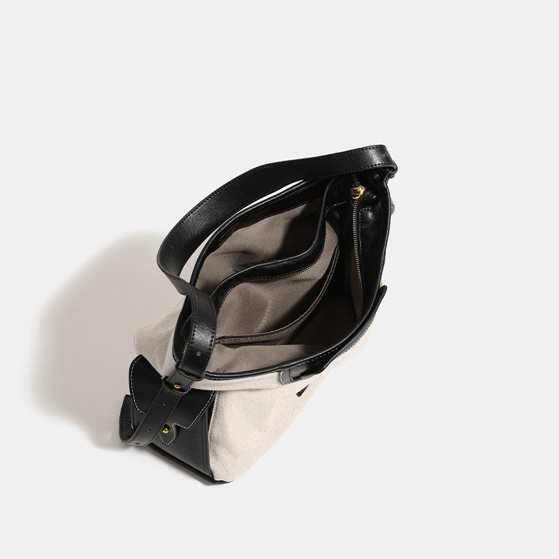 Off-white canvas hobo shoulder bag with black leather-look trim, gold-tone ring hardware, top zip closure, side pockets, and