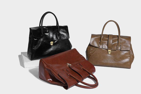 Strukturierte Henkeltasche in glänzender Lederoptik mit Überschlagverschluss, mittigem Riemen, goldfarbenem Drehverschluss und zwei Henkeln