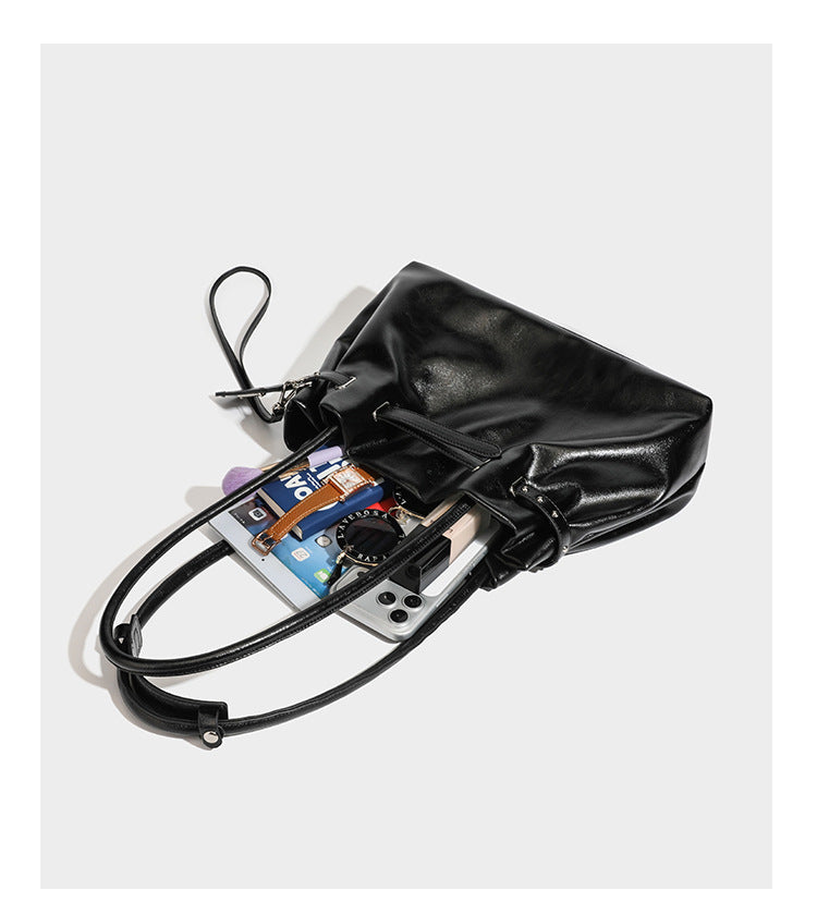 Glänzende schwarze, weich fallende Schultertasche mit gerafftem Abschluss, zwei langen Trageriemen, silberfarbenen Beschlägen und abnehmbarem Umhängeriemen
