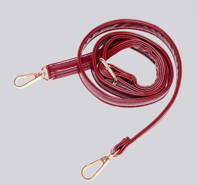 Glossy crescent hobo shoulder bag in deep burgundy with beaded wood tassel charm and gold-tone ring hardware, detail view 13