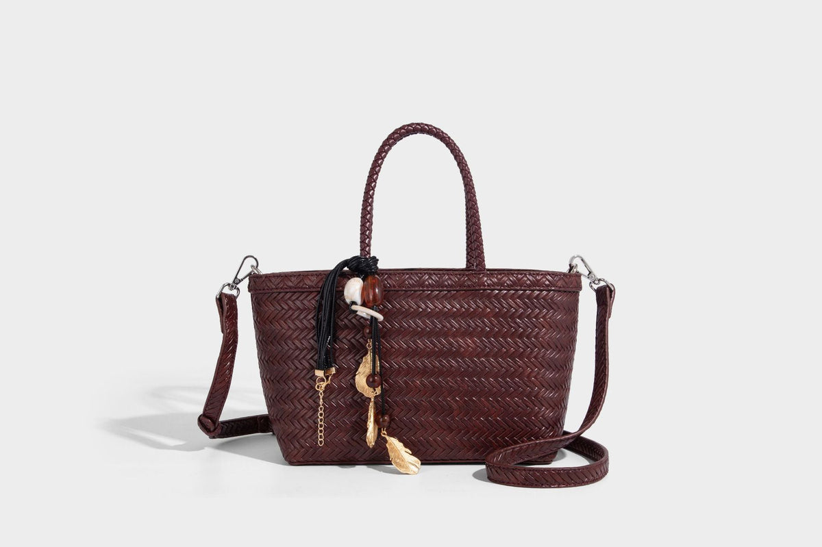 Structured chevron woven leather-look tote bag with braided top handles, gold feather charm, and adjustable shoulder strap